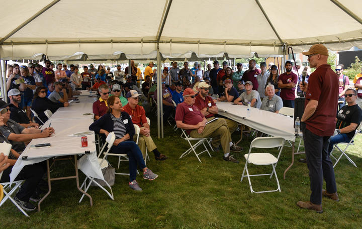 large crowd gathers under tent on grass